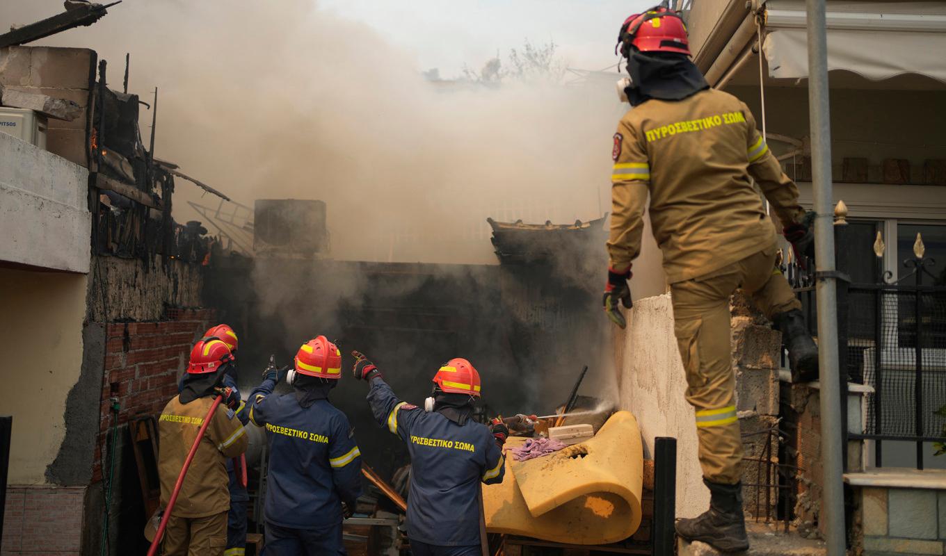 Brandmän bekämpar eldsvådorna vid en byggnad norr om Aten. Foto: Thanassis Stavrakis/AP/TT