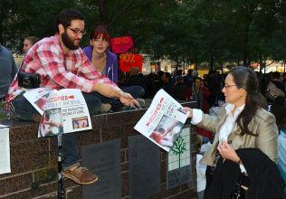 En volontär ger ett exemplar av tidningen "Occupy Wall Street" till en kvinna i Zucotti Park i New Yorks finansdistrikt på tordagseftermiddagen. (Foto: Zack Stieber/The Epoch Times
