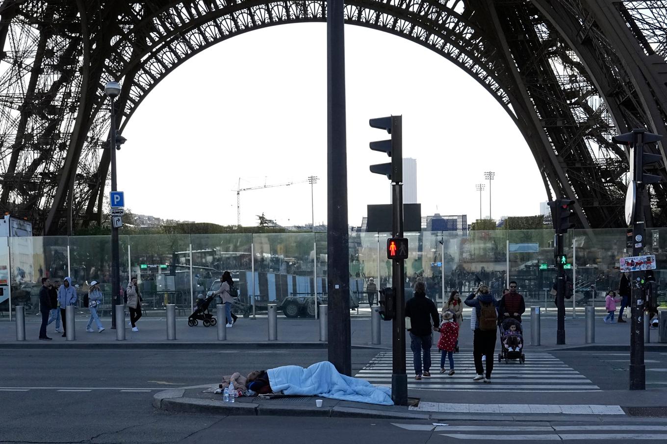 En hemlös person sover i närheten av Eiffeltornet i centrala Paris tidigare i april. Foto: Laurent Cipriani/AP/TT