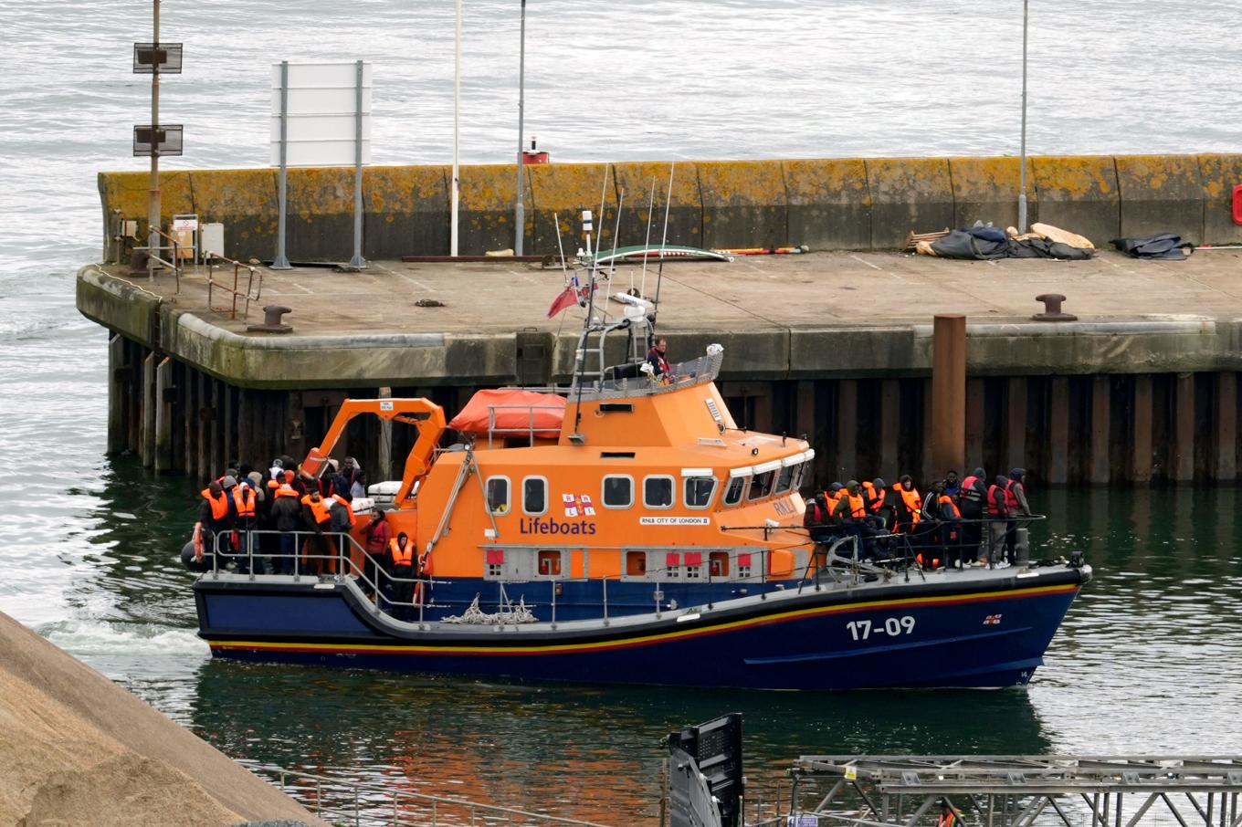 Händelsen sker samtidigt som Storbritanniens premiärminister Rishi Sunak vill avskräcka den farliga flyktingsmugglingen över Engelska kanalen. Bild på människor som tros vara migranter som förs till Dover i England. Foto: Gareth Fuller/PA via AP/TT
