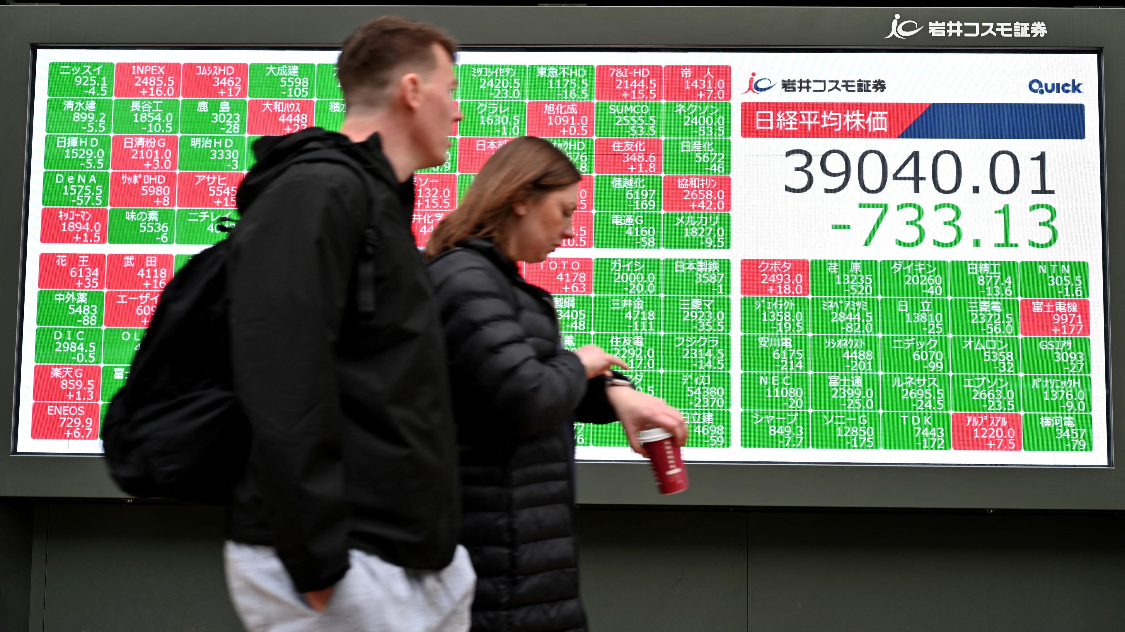 Människor går framför en elektronisk tavla som visar aktiekursen för Nikkei-indexet på Tokyobörsen i Tokyo i Japn den 5 april 2024. Foto: Kazuhiro Nogi/AFP via Getty Images