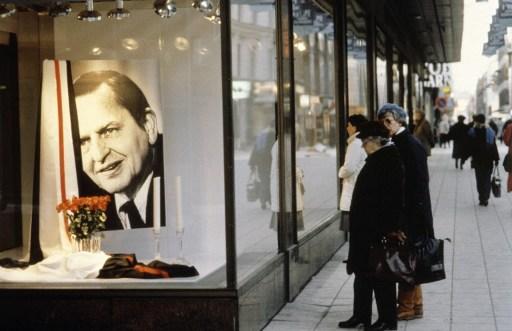 Förbipasserande tittar genom ett butiksfönster i mars 1986 på en gata i Stockholm, där man ställt ut bilder av Olof Palme som en hyllning till den svenska statsministern, som mördades den 28 februari 1986. (Foto: Pressensbild/ OFF/AFP)