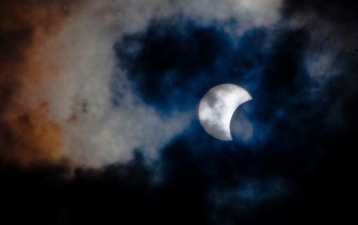 Denna bild tagen den 3 november 2013 visar en sällsynt solförmörkelse genom molnen från ön Teneriffa. Bredden av förmörkelsens skugga var 58 kilometer och den maximala tid som månen täckte solen helt, var 1 minut 40 sekunder på den spanska ön Teneriffa. (Foto: Desiree Martin/AFP)

