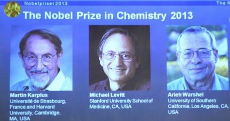 Dagens Nobelpristagare Martin Karplus, Michael Levitt och Arieh Warshel visas på en skärm under presskonferensen hos Kungliga Vetenskapsakademien. (Foto: Jonathan Nackstrand / AFP)