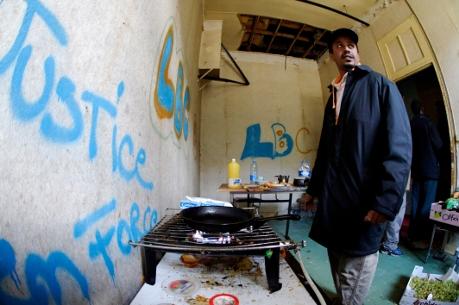 En flykting från Somalia lagar mat i en övergiven militärbarack i Pontoise i västra Paris. Där fanns varken elektricitet eller drickbart vatten. Bilden är från oktober 2009. (Foto: Lionel Bonaventure / AFP)