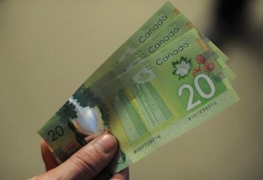 En man visar upp kanadensiska sedlar i Washington den 14 januari i år. (Foto: Nicholas Kamm / AFP)