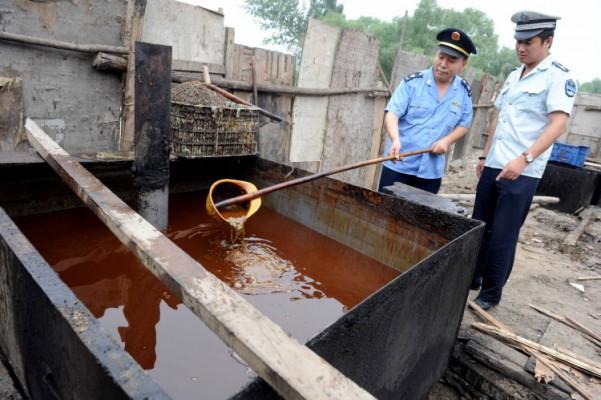 Kinesisk polis undersöker illegal matolja, "rännstensolja", som togs i beslag vid en razzia i Peking den 2 augusti 2010 efter att rapporter gjort gällande att upp till en tiondel av Kinas matolja tillverkas illegalt och kan innehålla cancerogena ämnen. (Foto: STR/AFP/Getty Images)