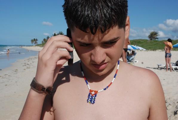 En pojke använder sin mobiltelefon på en strand den 26 maj 2010 i Havanna. (Foto: STR/ AFP/ Getty Images)