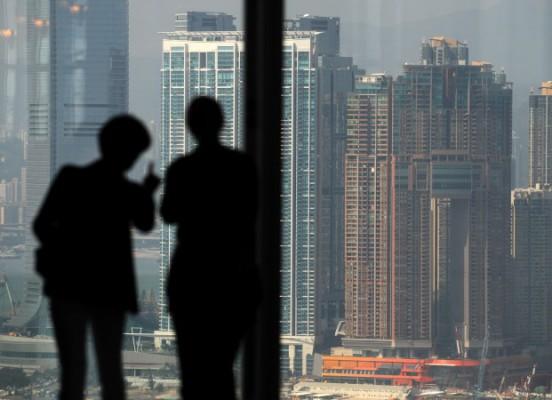 Två personer tittar ut mot skyskraporna på Kowloonhalvön från Hongkongön den 27 oktober 2010. En ny rapport visar att 315 kineser har en förmögenhet på över 1 miljard dollar, vilket är förvånande då det för tio år sedan inte fanns några miljardärer i Kina. (Foto: Antony Dickson/AFP/Getty Images)