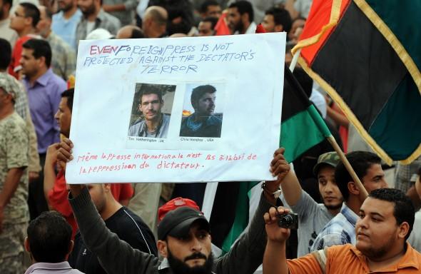 En libysk demonstrant håller upp en affisch som visar bilder av två utländska journalister, Tim Hetherington (t.v) och Chris Hondros, som dödades i staden Misrata den 20 april. (Foto: Saeed Khan / AFP / Getty Images)
