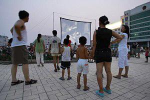 Folk ser på film vid en utomhusbio efter en jordbävning den 4 juli, i Wen’ans län, Hebeiprovinsen, Kina. (Foto: Cancan Chu/Getty Images)