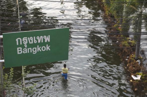En man vadar genom flodvattnet under Bangkoks skylt i Rangsits stadsdel i utkanten av Bangkok den 15 november 2011. (Foto: Saeed Khan / AFP / Getty Images)