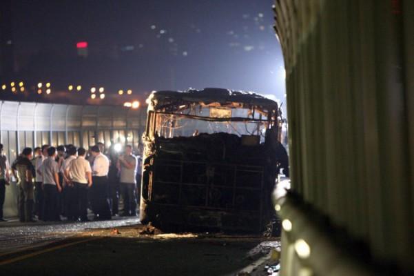 Bilden från den 7 juni 2013 visar utredare vid platsen där en buss fattade eld på en snabbväg för bussar i staden Xiamen i Fujianprovinsen, Kina. Bussen övertändes på några minuter under rusningstid, varvid 47 personer dödades och fler än 30 skadades. Utredare sade till statliga medier den 8 juni att den hade stuckits i brand avsiktligt. (STR/AFP/Getty Images)