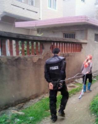 En kvinna leder en polis som tillfångatagits efter en konflikt kring markstölder i Dongwiao, Fujianprovinsen, den 11 maj 2013. (Molihua.org)
