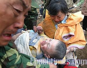 Lille Langzhens farföräldrar gråter av lättnad då de ser sitt barnbarn räddas ur de rasade husmassorna. 13 maj i staden Mianyang, Sichuan. (Foto: The Epoch Times)