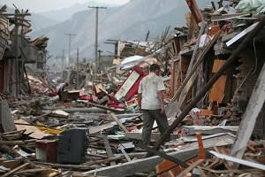 En överlevande som letar bland ruinerna efter användbara föremål. Experter uppskattar att de ekonomiska förlusterna efter jordbävningen uppgår till ungefär 525,2 miljarder yuan. (Foto: AFP)