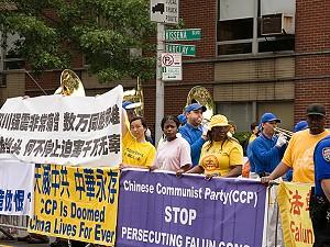 Falun Gong-utövare håller upp banderoller när marschbandet Tian Guo spelar. (Ben Kaminsky/ Epoch Times)
