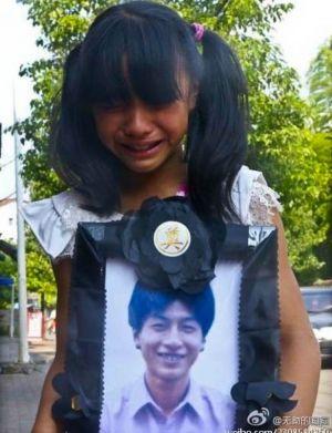 En 10-åring håller upp begravningsfotografiet på sin far, Huang Guohui. (Foto från Weibo.com)