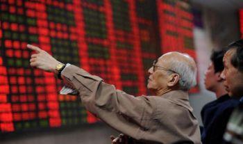 En kinesisk börsspekulant kontrollerar börspriserna på en aktiemäklarfirma i Shanghai.(Foto: Mark Ralston / AFP)
