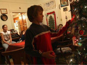 Mathew Woods 11 år justerar en prydnad i familjens julgran i Wilmington, Ohio. Hans far- och morföräldrar har precis berättat att det inte blir några julklappar från dem i år. (Foto: John Moore / Getty Images)
