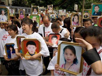 Föräldrar till skolbarn som dödades när Xinjians grundskola rasade samman i jordbävningen den 12 maj gråter medan de håller upp bilder på barnen. En minnesceremoni hölls under barnens dag, 1 juni 2008, på det förödda skolområdet i Dungjiangyan. (Foto: Andrew Wong/Getty Images)