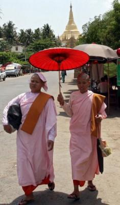 Buddhistiska nunnor skyddar sig mot solen med ett parasoll när de går längs en gata i Rangoon den 10 maj 2010. (Foto: AFP/Getty Images)