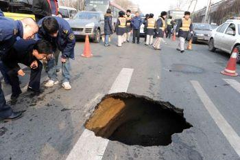 Kinesiska arbetare inspekterar ett slukhål på en gata i Peking den 8 februari. Slukhål är välkända geologiska fenomen som är vanligast i områden där man ägnat sig åt omfattande gruvdrift. (Foto: AFP/Getty Images)
