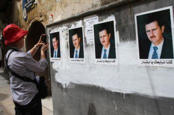 En turist fotograferar en vägg dekorerad med affischer av Syriens president Bashar al-Assad i den gamla staden i Damaskus den 2 april 2011. (Foto: Anwar Amro/AFP/Getty Images)
