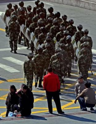 Invånare betraktar kinesiska soldater som patrullerar i den autonoma tibetanska prefekturen Ganzi i Sichuanprovinsen, den 23 mars 2008. (Teh Eng Koon/AFP/Getty Images)