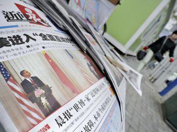 En kvinna i Shanghai går förbi en tidningskiosk där man visar kinesiska tidningar som rapporterar om USA president Barack Obamas besök i Kina. (foto: Philippe Lopez/AFP/Getty Images)