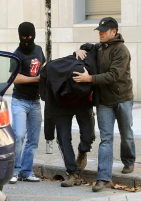 En oidentifierad person som misstänks vara medlem i Segi, en förbjuden ungdomsgrupp som tros ha anknytning till den väpnade baskiska separatiströrelsen ETA, eskorteras till en polisbil den 24 november 2009, i den baskiska staden San Sebastian i norra Spanien. (Rafa Rivas/Getty Images