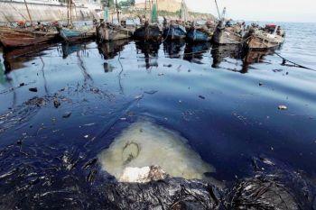 En båt och skräp som flyter omkring i en oljefläck i Gula havet. Efter en brand vid en pipeline i Dalian i Liaoningprovinsen skedde ett stort oljeutsläpp. (Foto: AFP/Getty Images)