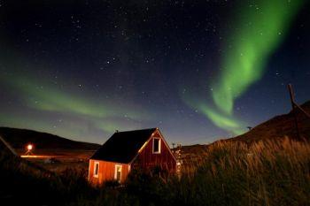 Norrsken, eller aurora borealis, skimrar i skyn vid den grönländska staden Kangerlussuaq. Norrsken inträffar oftast mellan september och oktober och från mars till april och är en populär turistattraktion. (Foto: Uriel Sinai/Getty Images)