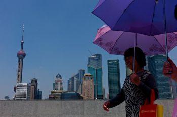 Affärscentrum: Två kvinnor promenerar förbi Shanghais centrala affärsdistrikt. Kina har ett stort intresse av att utveckla dess egen globala investeringsbank för att konkurrera med banker i Europa och USA. 
