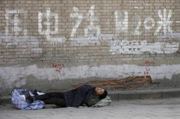 En petitionär sover på en tom gata i vad som är kvar av ett “petitionärskvarter”, som rivits inför OS. (Foto: Peter Parks/AFP/Getty Images)