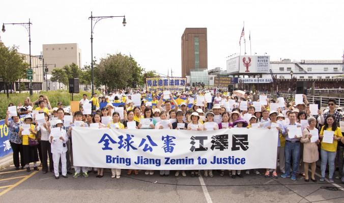 Falun Gong-utövare håller upp banderoll med sitt klagomål vid ett massmöte framför det kinesiska konsulatet i New York den 3 juli 2015 till stöd för de globala satsningarna på att brottsanmäla Jiang Zemin. (Foto: Larry Dye/Epoch Times)
