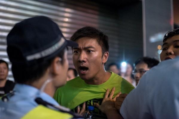 Mannen skriker åt polisen för att denne inte skyddar demokratirörelsens demonstranter från att bli attackerade av betalda gangsters i Hongkong 4 oktober 2014. Tiotusentals var ute i en fridfull demonstration i centrala Hongkong trots polisens  trakasserier. (Foto: Alex Ogle / AFP / Getty Images)
