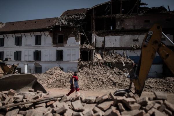 En kvinna promenerar förbi resterna av rasade hus på världsarvet Durbartorget i Katmandu, efter den kraftiga jordbävning som drabbade Nepal den 25 april. Antalet döda har nu passerat 8 000, enligt officiella siffror. (Foto: Philippe Lopez/AFP/Getty Images)