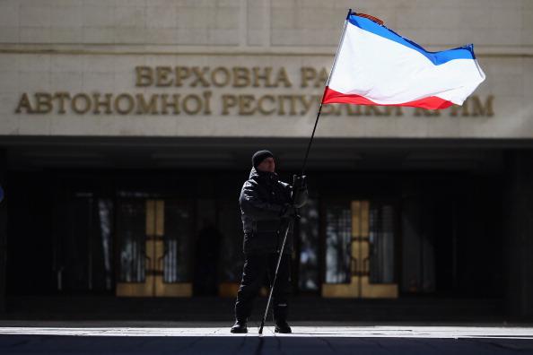 En man stod på måndagen med Krims ryskinspirerade flagga framför Krims parlamentsbyggnad i Simferopol, efter att en icke internationellt erkänd folkomröstning på söndagen visade att en stor majoritet av de röstande vill förenas med Ryssland. (Foto: Dan Kitwood/Getty Images) 
