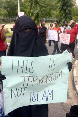 På skylten som kvinnan håller står det ”Detta är terrorism inte islam”. En demonstration hölls i Lagos för frisläppandet av de saknade skolflickorna den 5 maj. (Foto: Pius Utomi Ekpei / AFP/Getty Images)