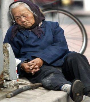 En gammal kvinna vilar sig vid ett övergångsställe i Peking. (Foto: Frederic J.Brown/AFP/Getty Images) 