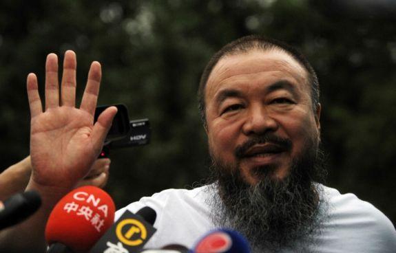 Den frispråkige konstnären Ai Weiwei vinkar till reportrar utanför sin ateljé i Peking den 23 juni. Ai släpptes från sitt tre månader långa frihetsberövande på villkor att han inte skulle tala med media eller gå in på sociala medier på ett år. (Foto: Peter Parks/AFP/Getty Images) 