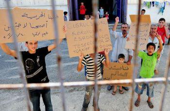 Inte förskonade: Syriska minderåriga håller upp plakat och skanderar slagord tillsammans med äldre män efter att ha flytt från Syrien till Turkiet. Uppskattningsvis har 72 barn dödats av syriska säkerhetsstyrkor sedan demonstrationerna mot regeringen inleddes i mars. (Foto: Mustafa Ozer/AFP/Getty Images)