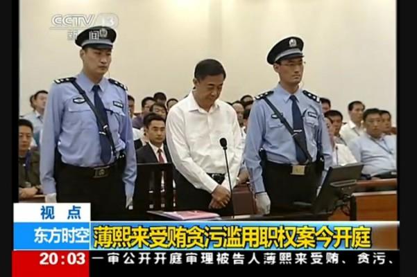 Den förre politbyråmedlemmen Bo Xilai står mellan två vakter i Jinans mellanliggande domstol i Shandongprovinsen under rättegångens första dag, den 22 augusti. Bo var stridslysten, men rättegången utelämnade nyckeldetaljer kring hans aktiviteter medan han var vid makten. (Foto: Skärmdump/Epoch Times)