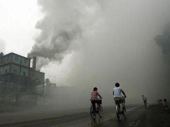 Cyklister passerar genom tjocka luftföroreningar från en fabrik i Yutian, tio mil öster om Peking i Hebeiprovinsen, 2006. Förekomsten av cancer och dödsfall i området är hög och många bybor som försöker få upprättelse trakasseras. (Foto: Peter Parks/AFP/Getty Images)