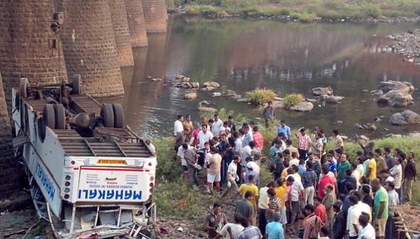 Indisk räddningstjänst och åskådare har samlats runt bussvraket som föll ned från en bro vid Khed, söder om Mumbai den 19 mars 2013. (Foto: STRDEL/AFP/Getty Images)
