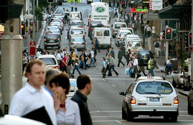 Bilar och fotgängare blandas på en av de livligt trafikerade gatorna i Sydney. Människor som lever nära hårt trafikerade vägar har mer slem i luftvägar och andningssvårigheter visar en ny studie från Schweiz. (Foto: AFP/Rob Elliot)
