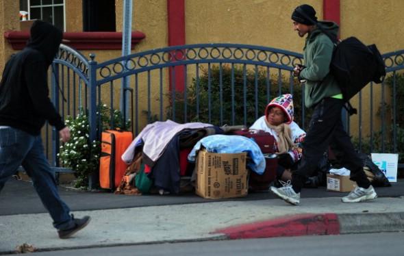 En hemlös kvinna sitter bland sina tillhörigheter på en trottoar i Los Angeles den 6 december 2011. (Foto: Frederic J. Brown/AFP/Getty Images)