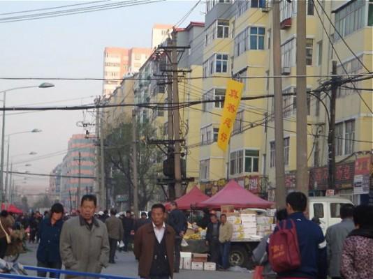 En banderoll där det står “Sanning, Godhet, Tålamod är bra” på en stor köpgata. (Bild från Minghui.org)  
