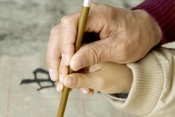 En far lär sitt barn kinesisk kalligrafi, en konstform som har utvecklats genom århundraden. Den omfattar estetiska aspekter såsom rytm, design, prydlighet och skönhet. (Foto: Fergus Wang /Fotolia)